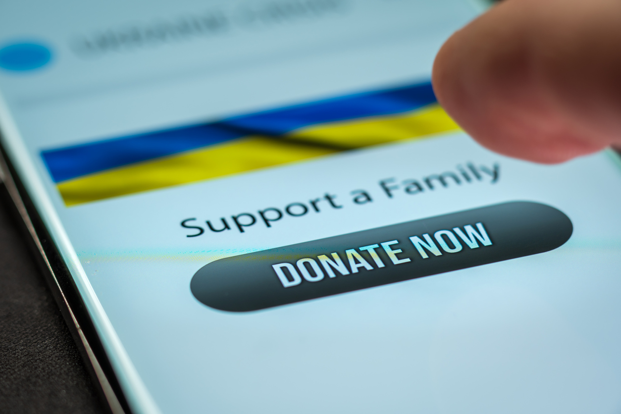 Close-up finger pressing donate button on smartphone screen. Donation money online concept