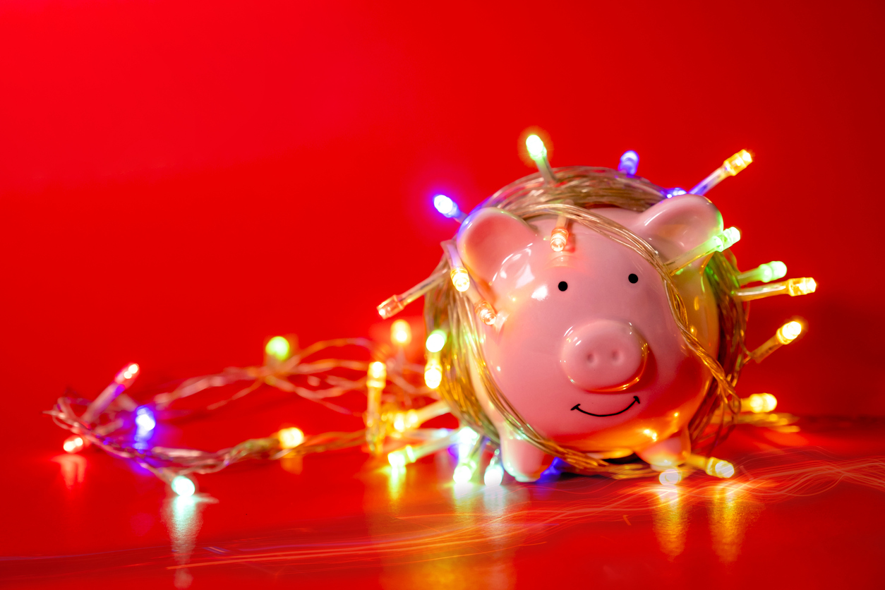 Pink piggy bank with Christmas string lights on happy December festival in Red background, Enjoy savings for spending money on the holiday's concept.